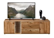 Frontansicht eines breiten TV-Lowboards aus hellem Massivholz mit zwei seitlichen Türen und drei Schubladen, mittigem Akzent in Steinoptik und schwarzen Griffen, darauf ein Fernseher und Dekoration
