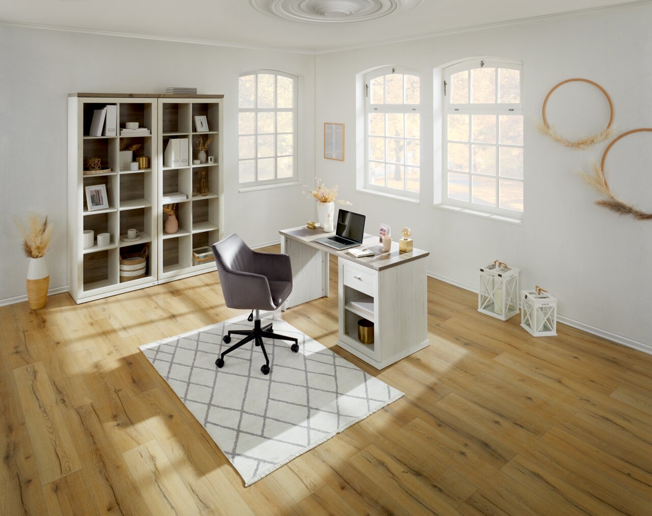 Heller, moderner Schreibtisch in einem stilvollen Arbeitszimmer mit Blick auf ein großes Fenster, umgeben von Regalen und Dekorationen.