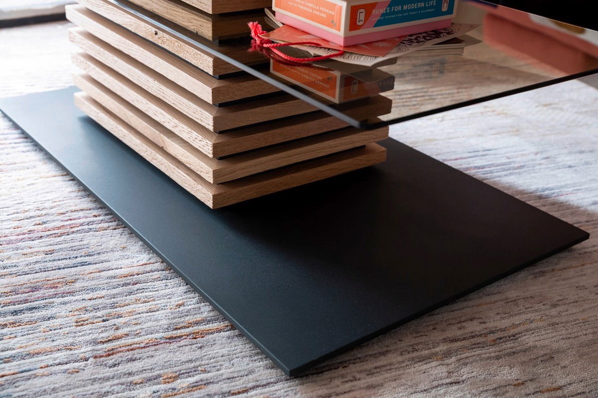 Moderner Couchtisch mit Glasplatte und gestapeltem Holzdesign, seitliche Perspektive