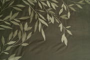 Bettwäsche mit elegantem Blattmuster in Nahaufnahme, dunkelgrüner Hintergrund mit hellen Blättern.