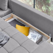 Graue Rundecke Ottli mit geöffneter Stauraumfunktion, gelbem Kissen und Zeitschriften, von oben betrachtet.