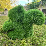 Groene, grasachtige eekhoorn-tuindecoratie, gezien vanaf de zijkant, geplaatst in de tuin.