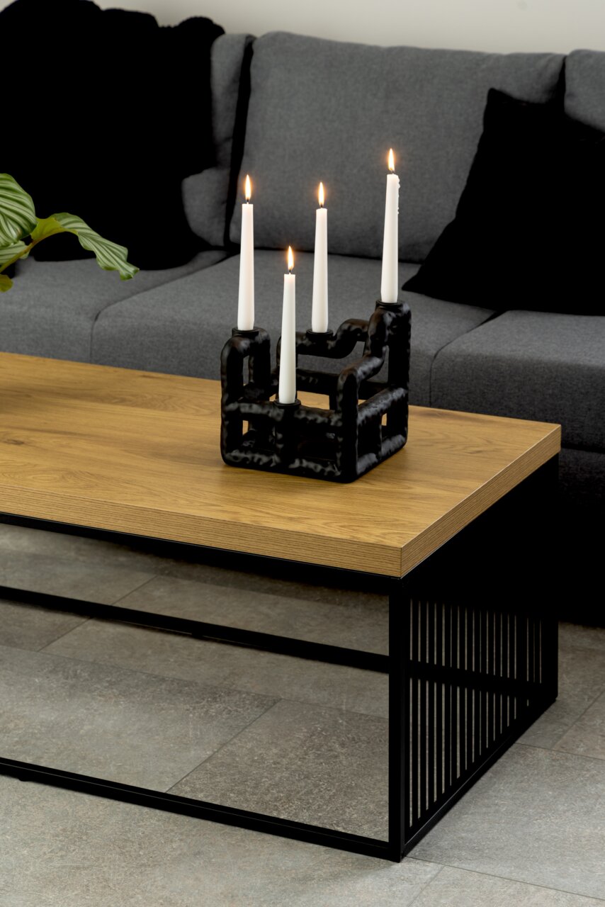 Moderner Couchtisch mit Holzplatte und schwarzem Metallgestell, seitliche Perspektive, dekoriert mit einem Kerzenhalter.