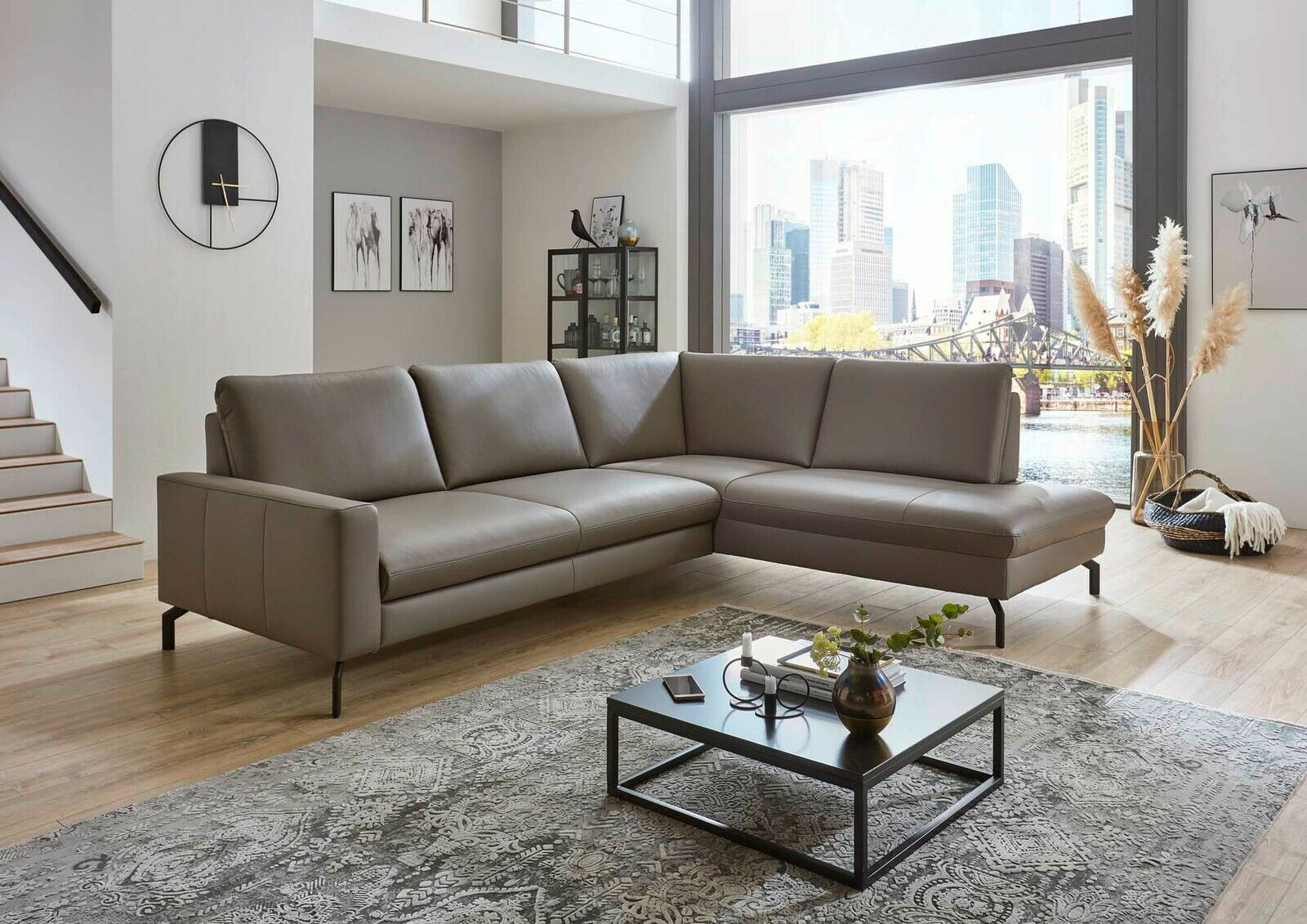 Moderne Polsterrundecke in einem stilvollen Wohnzimmer mit Blick auf die Stadt durch große Fenster, seitliche Perspektive.