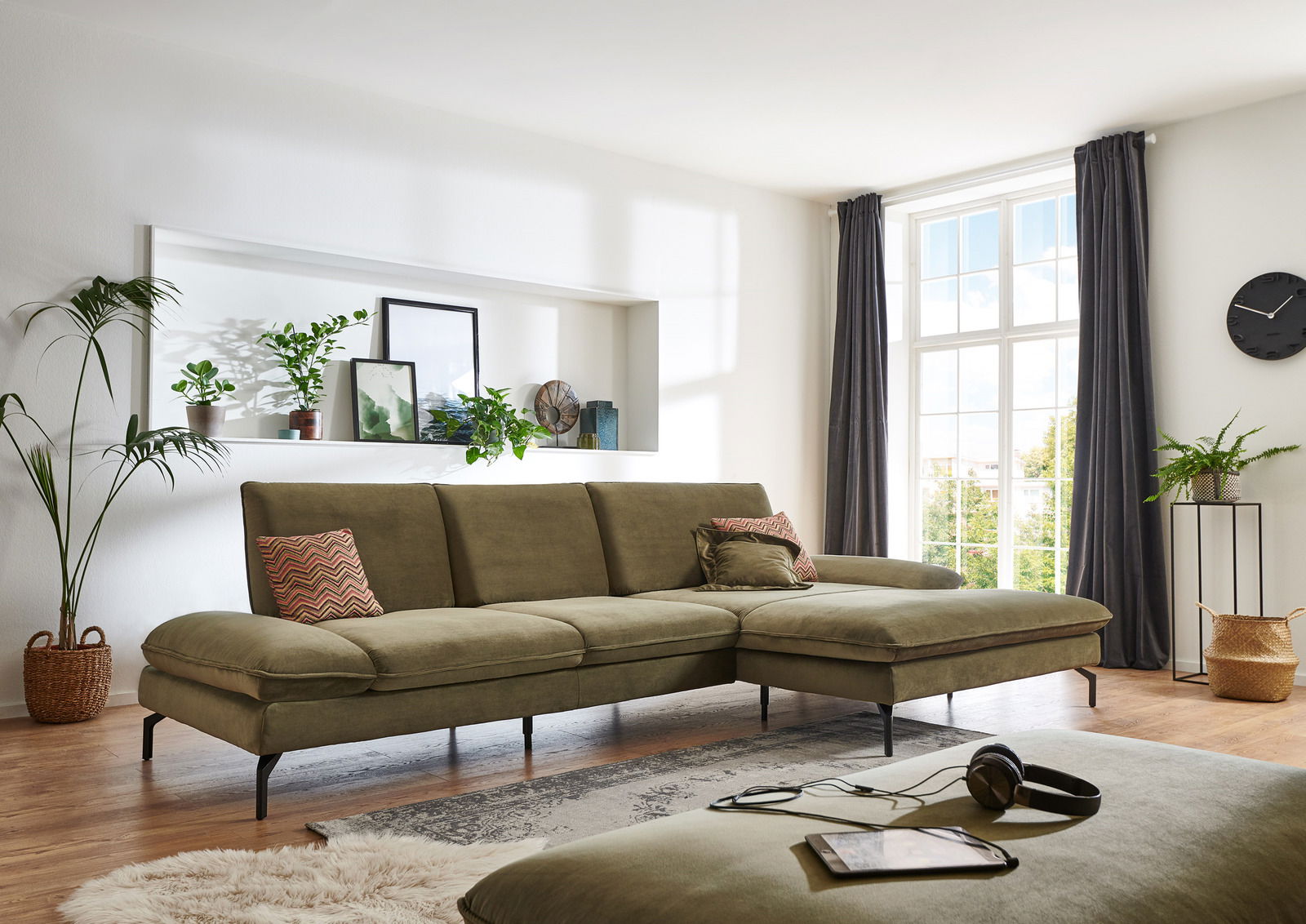 Grüne Longchairkombination in einem hellen Wohnzimmer, seitliche Perspektive mit großen Fenstern im Hintergrund.