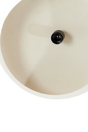 Close-up van een crèmekleurige hanglamp, van bovenaf gezien, met een zichtbare lamphouder in het midden.