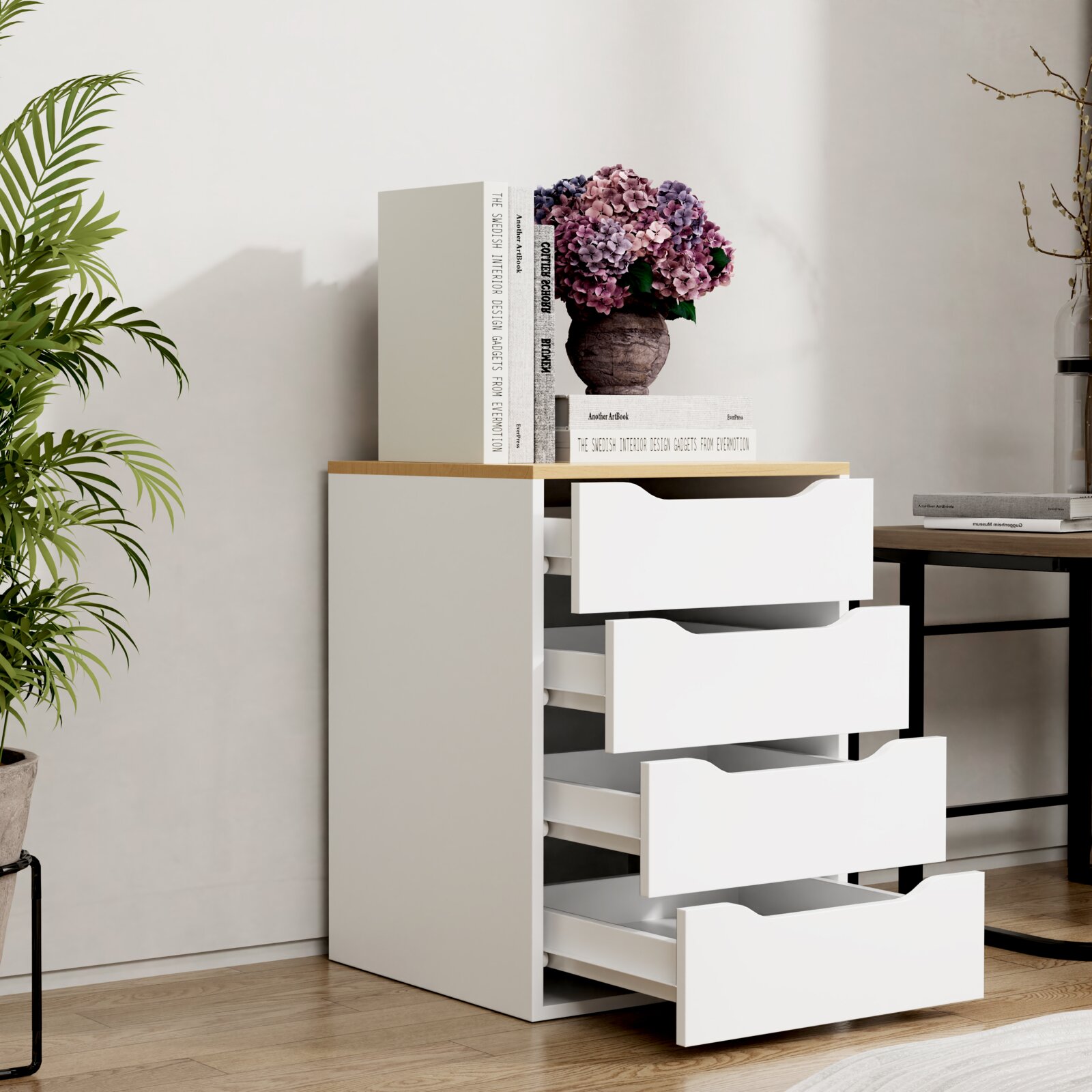 Moderne weiße Kommode mit vier geöffneten Schubladen und Holzplatte, dekoriert mit Büchern und Hortensienvase, im schrägen Frontblick in hellem Wohnraum