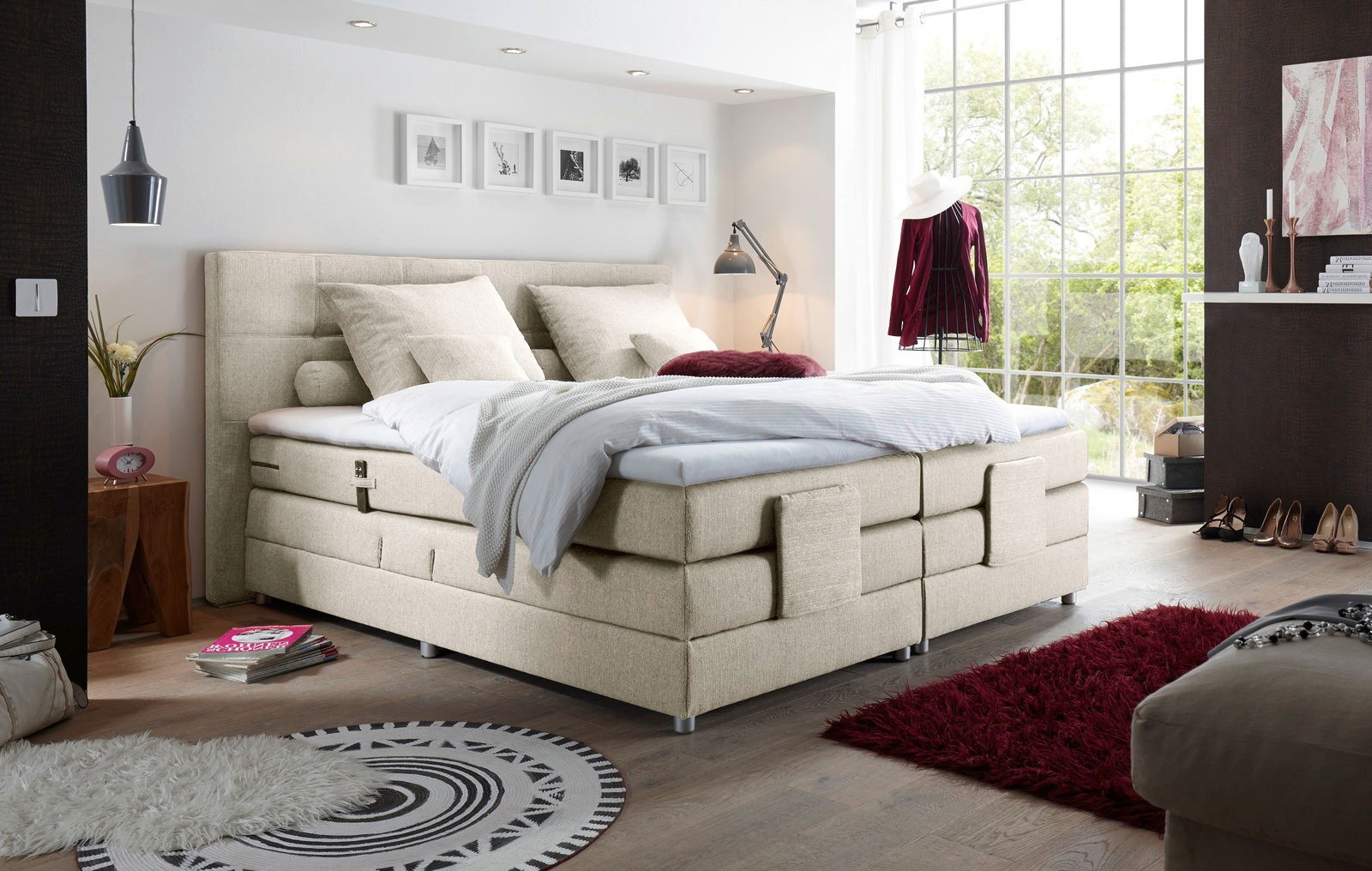 Boxspringbett in einem modernen Schlafzimmer mit großen Fenstern, seitliche Perspektive