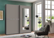 Schwebetürenschrank mit zwei Türen, einer davon mit Spiegel, in einem modernen Wohnzimmer mit Blick auf große Fenster.