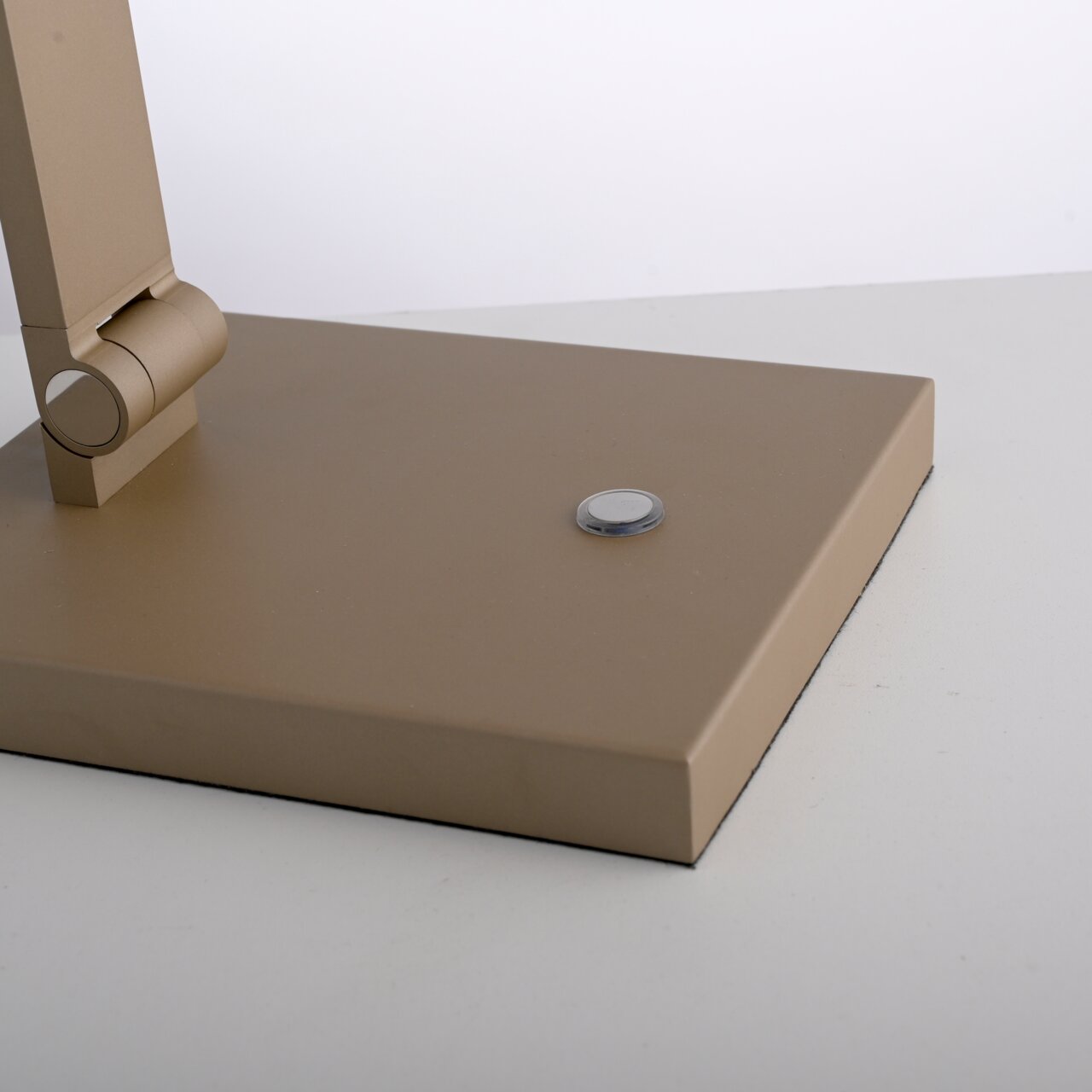 Nahaufnahme der Basis einer LED-Tischleuchte in Beige mit einem runden Schalter auf der Oberseite.