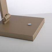 Nahaufnahme der Basis einer LED-Tischleuchte in Beige mit einem runden Schalter auf der Oberseite.