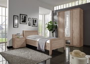 Komfortbett aus hellem Holz in einem modernen Schlafzimmer, seitliche Perspektive mit Nachttisch und Kleiderschrank.