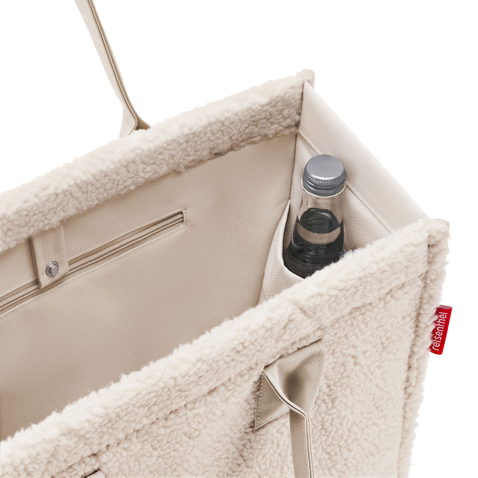 Innenansicht einer beigen Einkaufstasche mit weichem Futter, einer Flasche in der Seitentasche und einem Reißverschlussfach.
