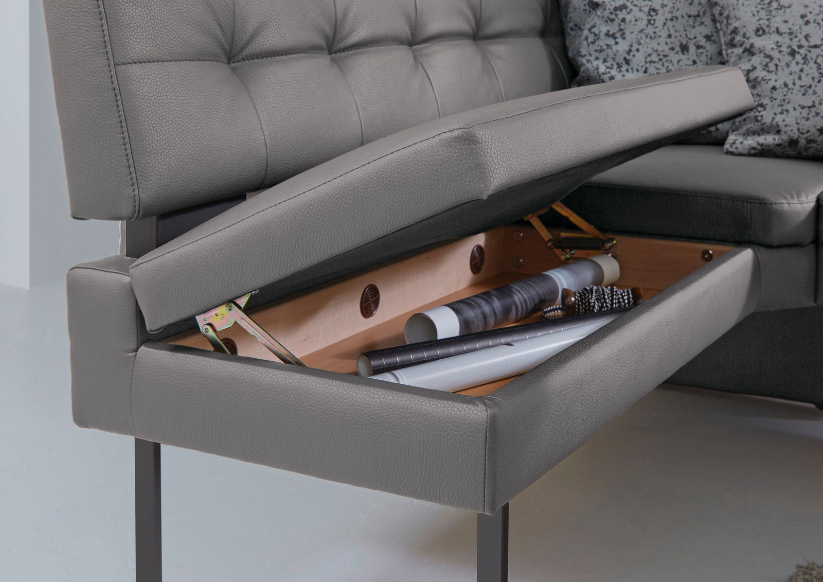 Detailansicht einer grauen Eckbank mit geöffneter Sitzfläche, die Stauraum zeigt.