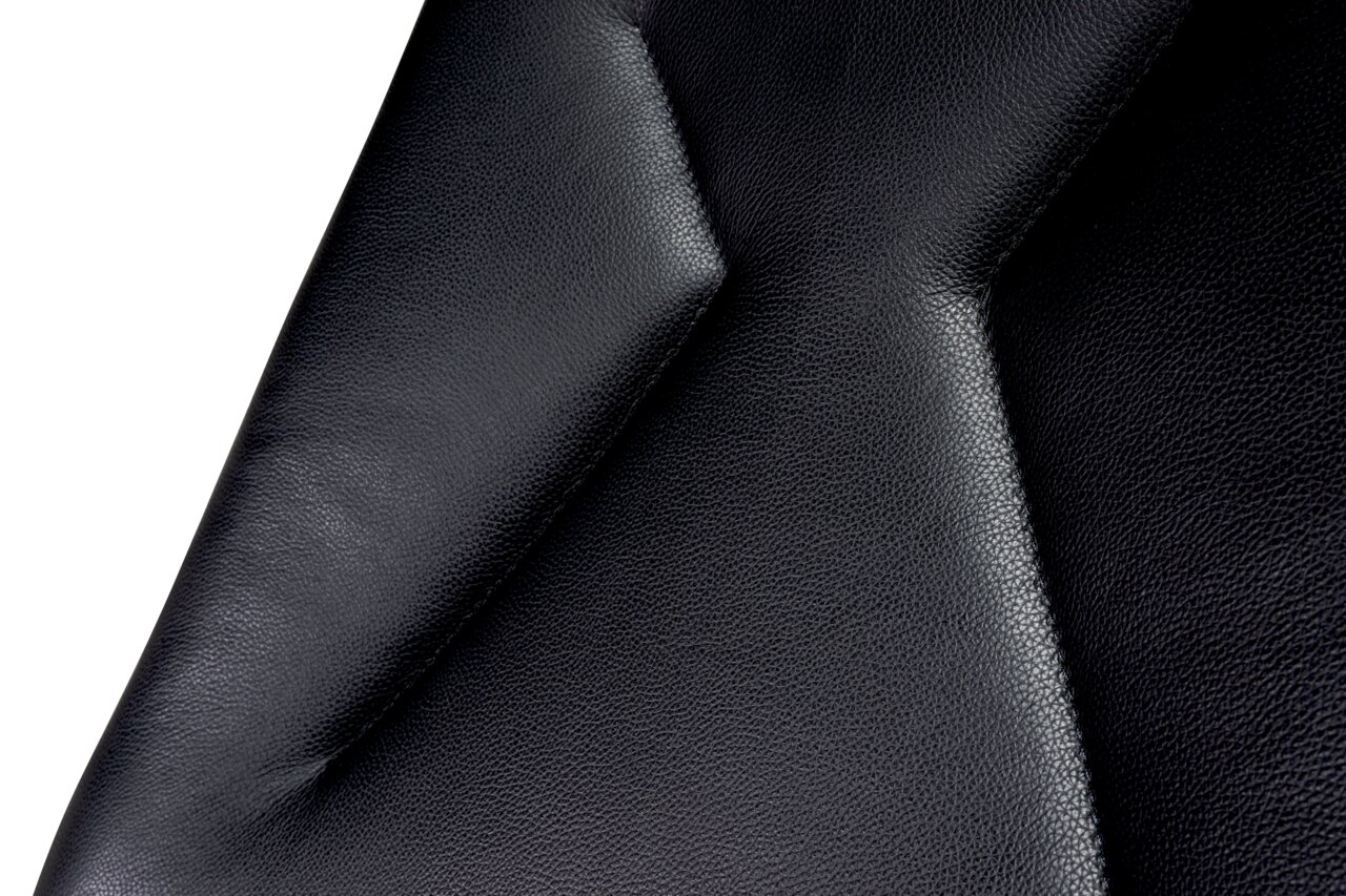 Nahaufnahme der schwarzen Lederpolsterung eines Chefsessels, seitliche Perspektive