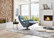 Moderner blauer Relax-Sessel in einem stilvollen Wohnzimmer mit Kamin und Panoramafenster, seitliche Perspektive.