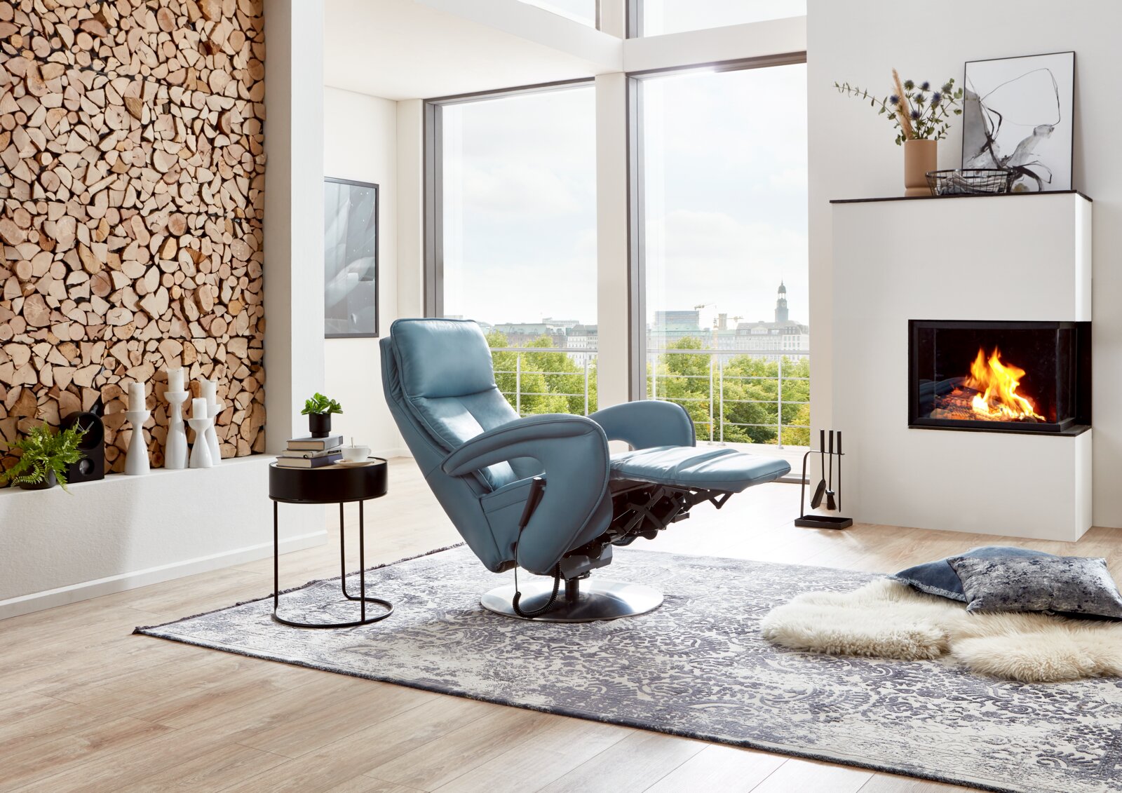 Moderner blauer Relax-Sessel in einem stilvollen Wohnzimmer mit Kamin und Panoramafenster, seitliche Perspektive.