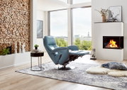 Moderner blauer Relax-Sessel in einem stilvollen Wohnzimmer mit Kamin und Panoramafenster, seitliche Perspektive.