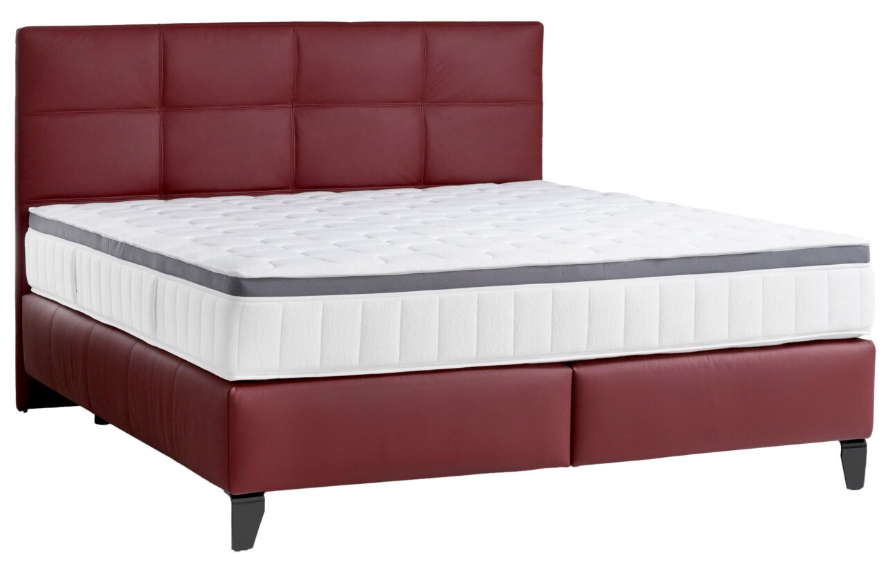 Boxspringbett mit rotem Kopfteil und weißer Matratze, seitliche Perspektive