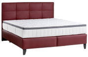 Boxspringbett mit rotem Kopfteil und weißer Matratze, seitliche Perspektive