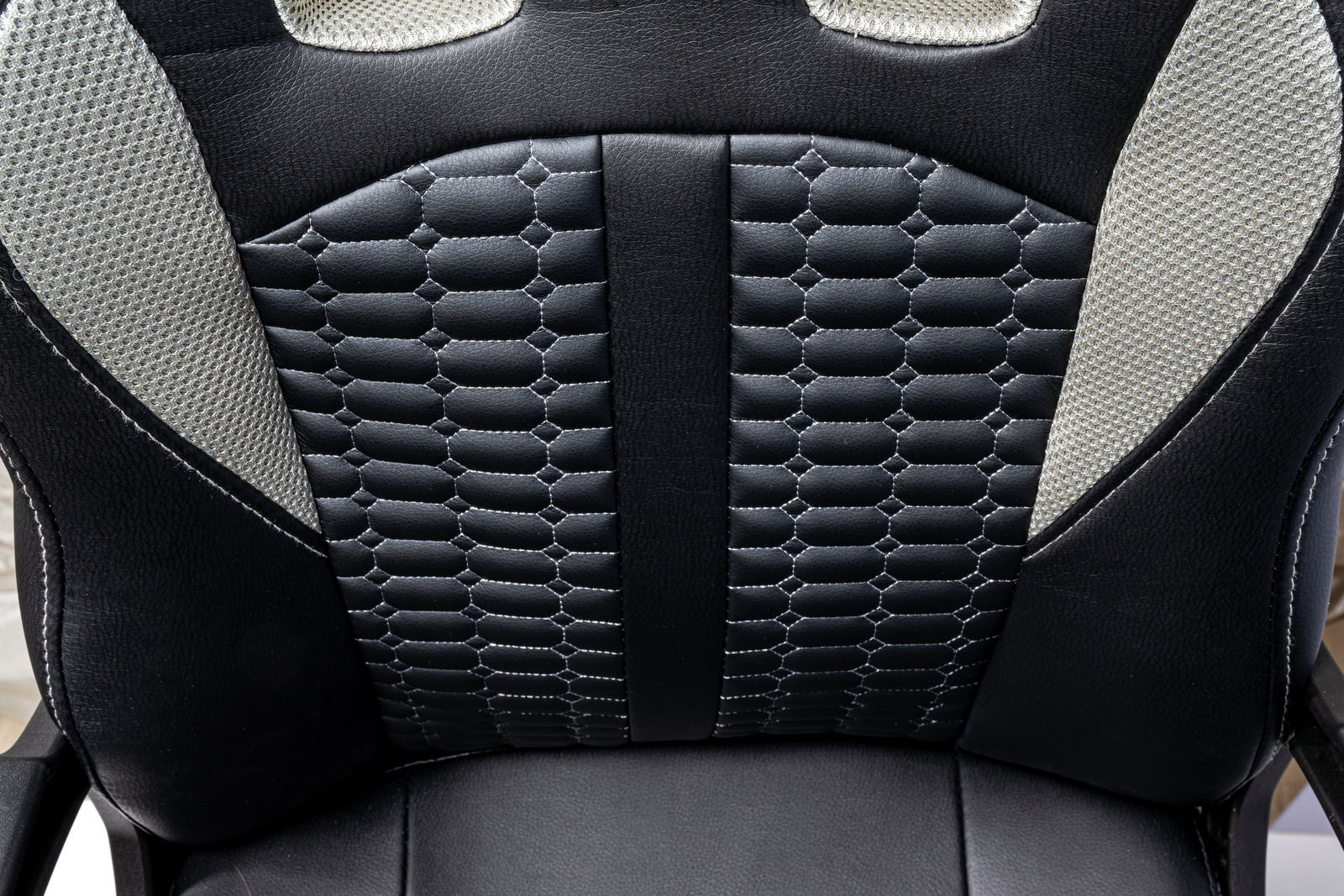 Nahaufnahme der Rückenlehne eines Gaming-Stuhls mit schwarzem, wabenförmigem Muster und grauen Akzenten, von vorne betrachtet.