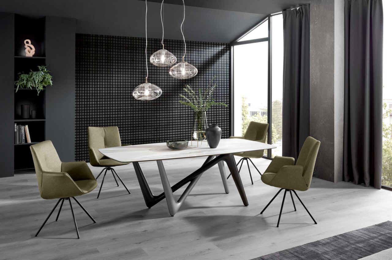 Moderne eethoek met vier olijfgroene fauteuils rond een witte tafel, zijaanzicht.