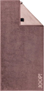 JOOP! Handtuch in Mauve mit heller Rückseite und JOOP!-Logo, teilweise umgeschlagen, Frontansicht schräg von oben