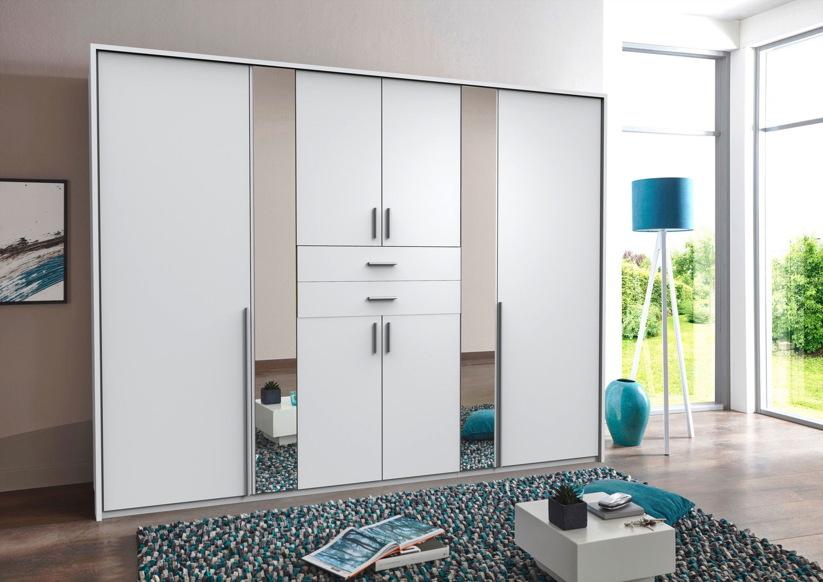 Moderner weißer Drehtürenschrank mit sechs Türen und Spiegel, frontal im hellen Raum mit großen Fenstern.