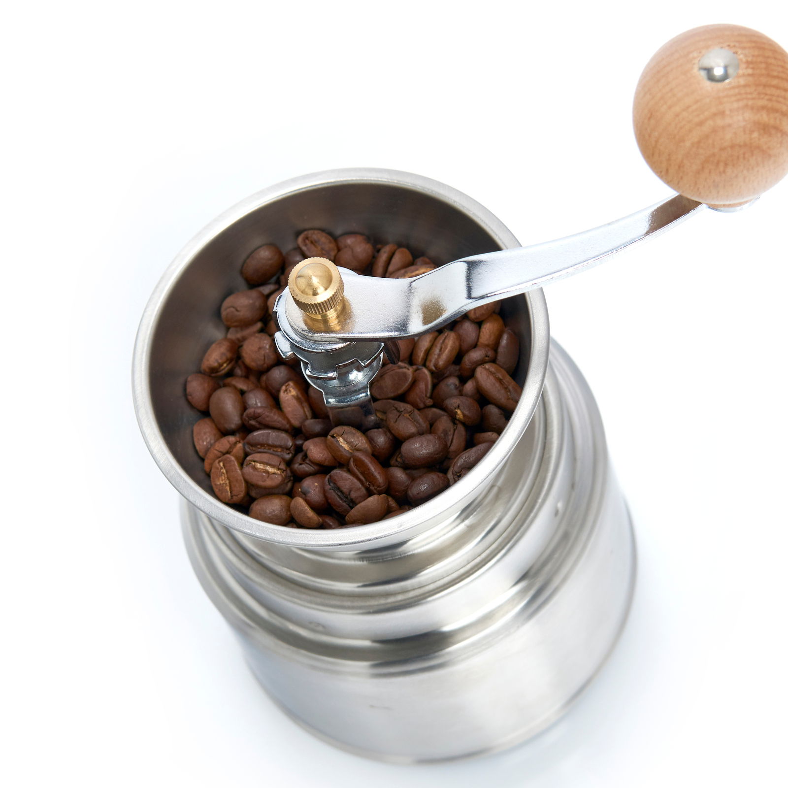 Manuelle Kaffeemühle aus Edelstahl mit Holzgriff, gefüllt mit Kaffeebohnen, aus der Vogelperspektive