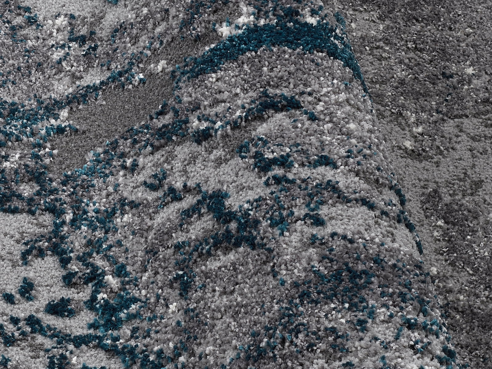 Nahaufnahme eines Designer-Teppichs mit grauen und blauen Mustern, aus einer schrägen Perspektive fotografiert.