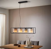 Moderne Hängeleuchte mit vier zylindrischen Lampenschirmen in einem rechteckigen Rahmen, von der Decke hängend über einem Esstisch, seitliche Perspektive.