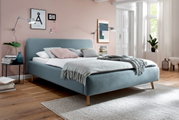 Modernes Polsterbett in hellblauem Stoff mit Holzfüßen, seitliche Perspektive, dekoriert mit Kissen und Decke in einem stilvoll eingerichteten Schlafzimmer.