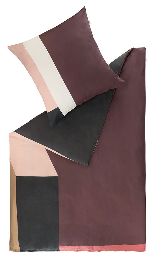 Bettwäsche-Set in geometrischem Design mit Kissen und Decke in verschiedenen Farbtönen, aus der Vogelperspektive fotografiert.