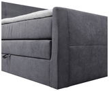 Seitliche Perspektive eines grauen Boxspringbetts mit gepolstertem Kopfteil und Matratze.