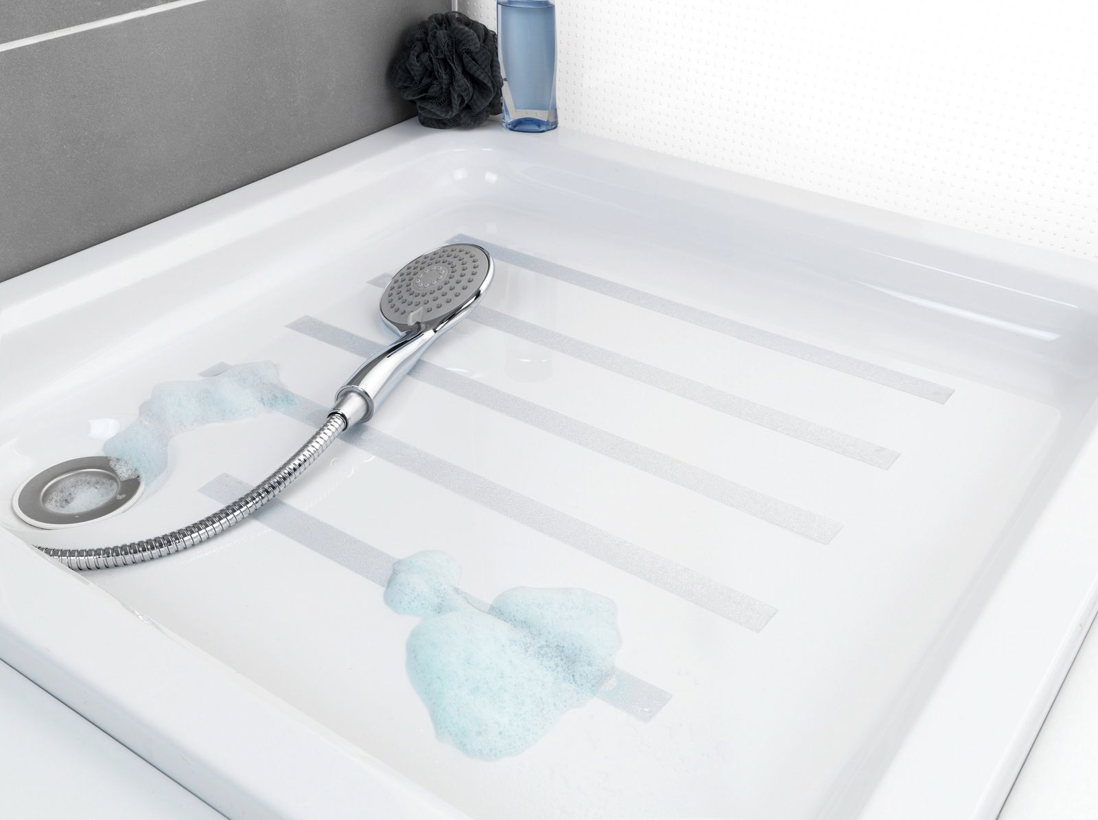 Blick von oben auf eine Duschwanne mit Anti-Rutschband und Duschkopf, umgeben von Seifenschaum.