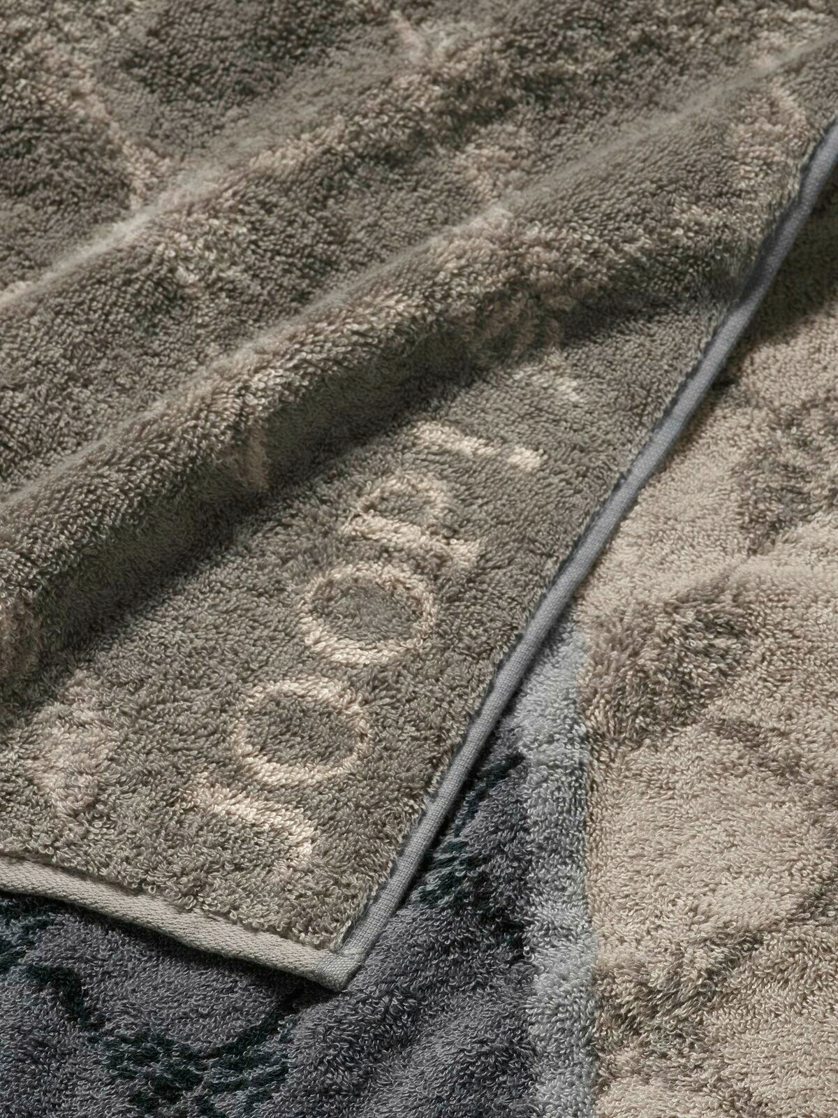 JOOP! Duschtuch SIGNATURE Nahaufnahme eines grauen und beigen Duschtuchs mit eingewebtem Muster und Schriftzug, von oben betrachtet.
