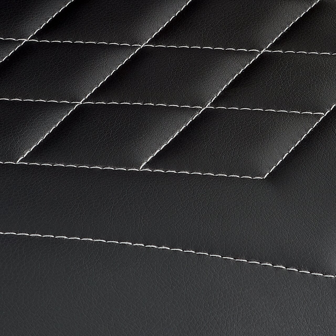Nahaufnahme der schwarzen, gesteppten Lederoberfläche eines Gamingstuhls mit weißen Nähten.