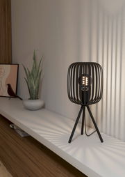 Moderne Tischleuchte mit schwarzem, gitterförmigem Lampenschirm und dreibeinigem Stativ, seitliche Perspektive