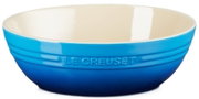 Blaue Le Creuset Keramikschüssel mit cremefarbener Innenseite und geprägtem Logo, freigestellt vor weißem Hintergrund, seitliche Ansicht leicht von oben