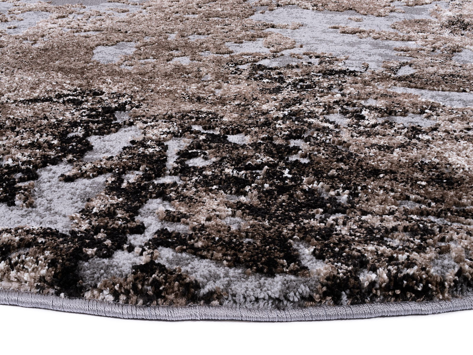 Nahaufnahme eines Designer-Teppichs mit abstraktem Muster in Erdtönen, seitliche Perspektive