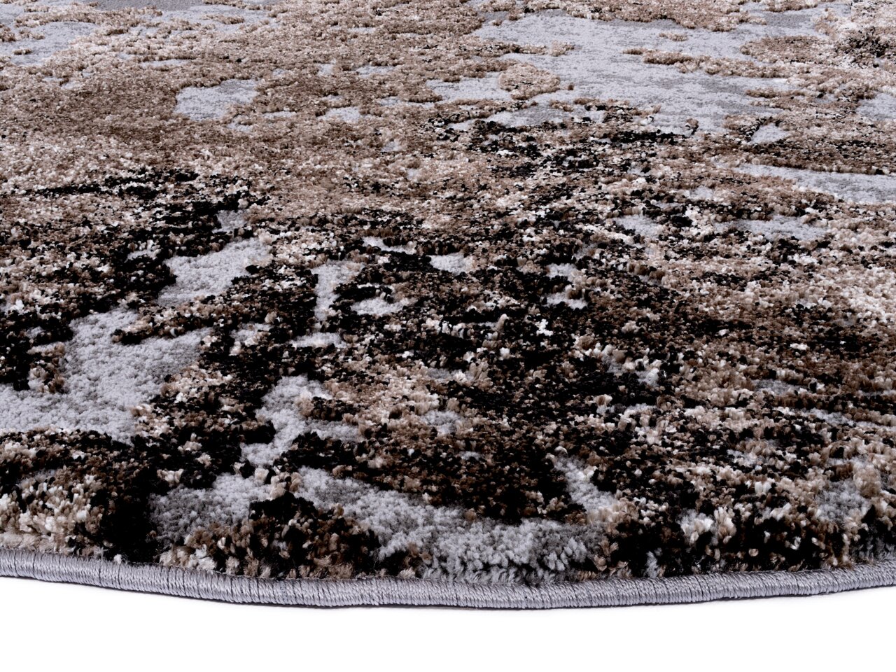 Nahaufnahme eines Designer-Teppichs mit abstraktem Muster in Erdtönen, seitliche Perspektive