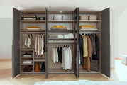 Open kast met zes draaideuren, voorzien van diverse vakken en kledingstangen, gevuld met kleding, koffers en dozen, gezien vanuit het vooraanzicht.