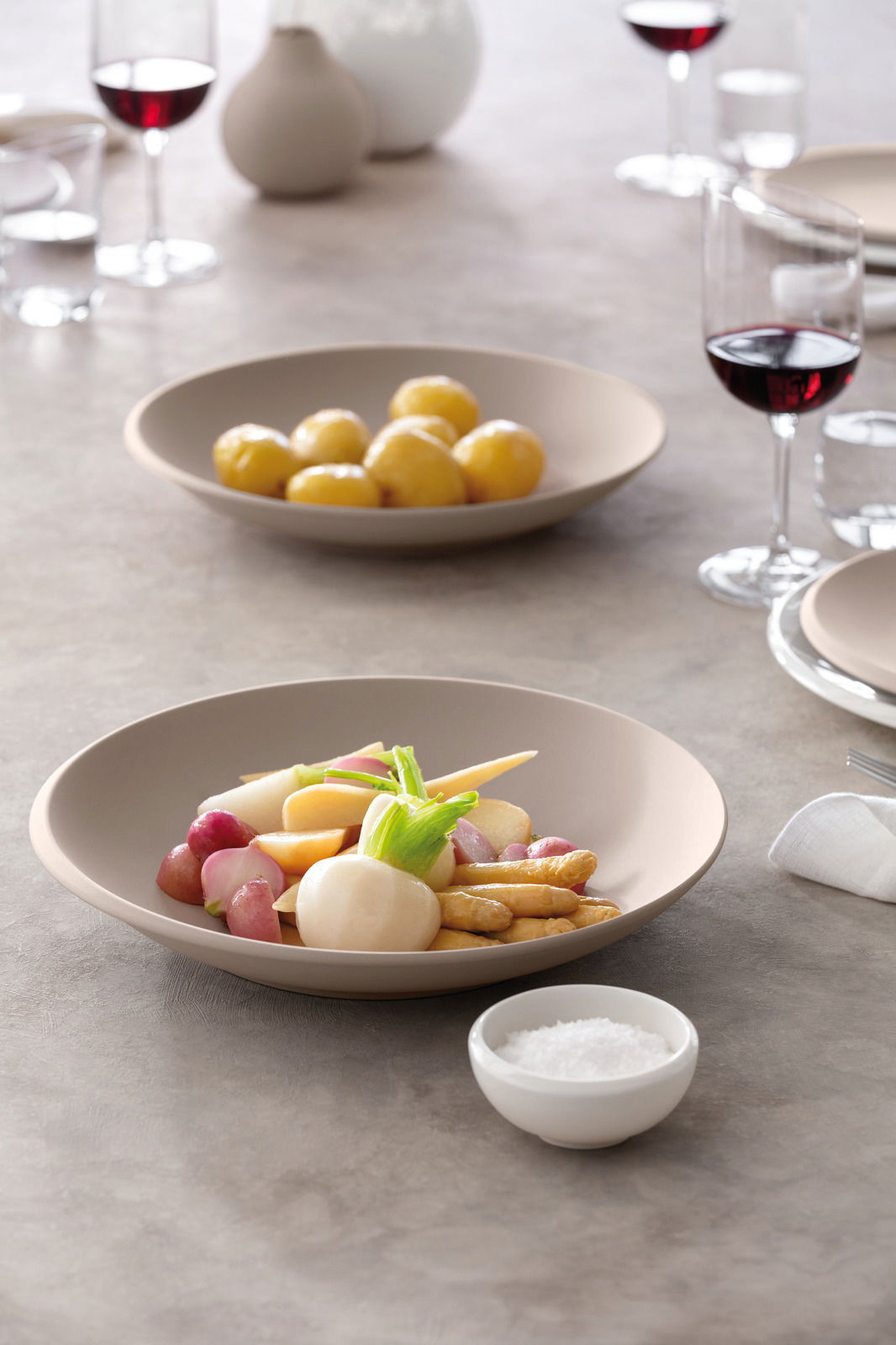 Villeroy & Boch Schale NewMoon 750ml beige NEW MOON Beige Schale NewMoon 750ml mit Gemüse, seitliche Perspektive, gedeckter Tisch mit Weingläsern.