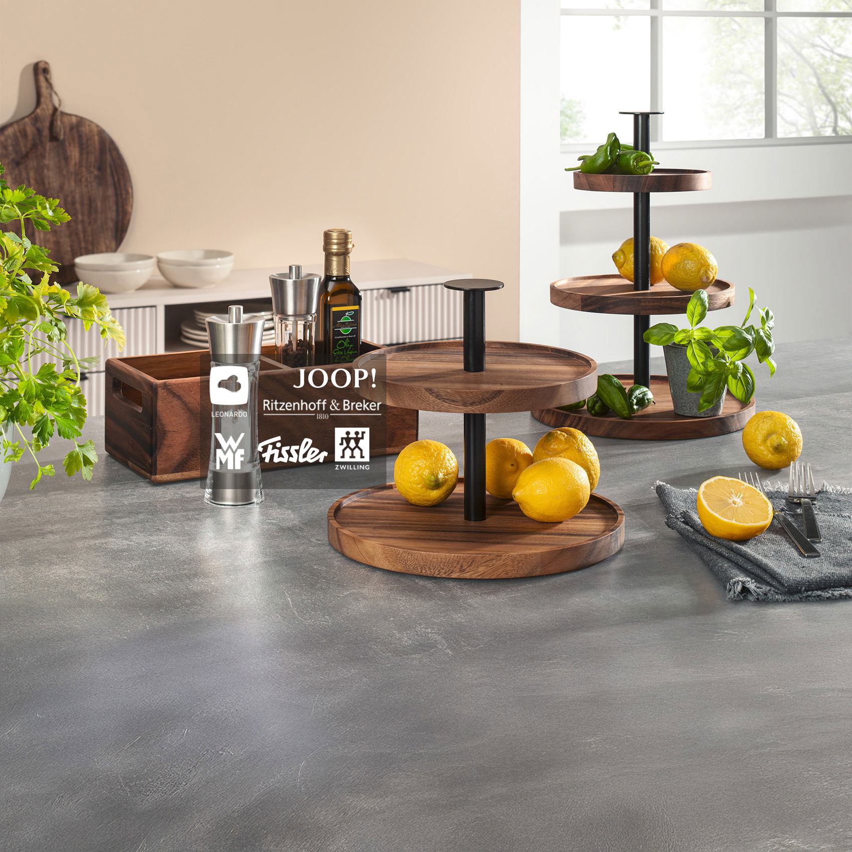 Moderne Küchenpräsentation mit Etageren aus Holz, frischen Zitronen, Kräutern und Markenartikeln wie WMF, Fissler und Zwilling