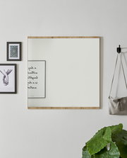 Moderner Wandspiegel mit Holzrahmen, frontal fotografiert, umgeben von Dekorationen wie Bildern und einer Pflanze.