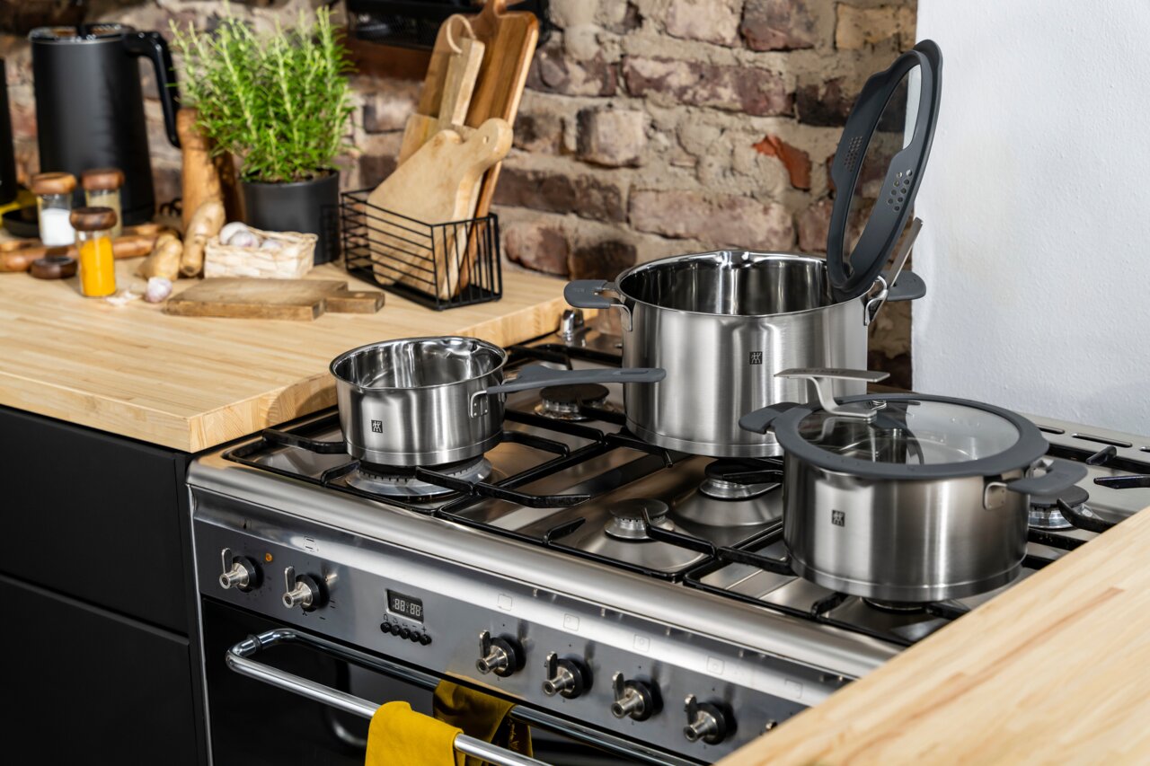 5-delige Simplify-pannenset van roestvrij staal op een fornuis in een moderne keuken, zijaanzicht