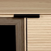 Nahaufnahme eines Holzschranks mit leicht geöffneter Schublade und schwarzem Griff, frontal aus leichter Seitenperspektive aufgenommen