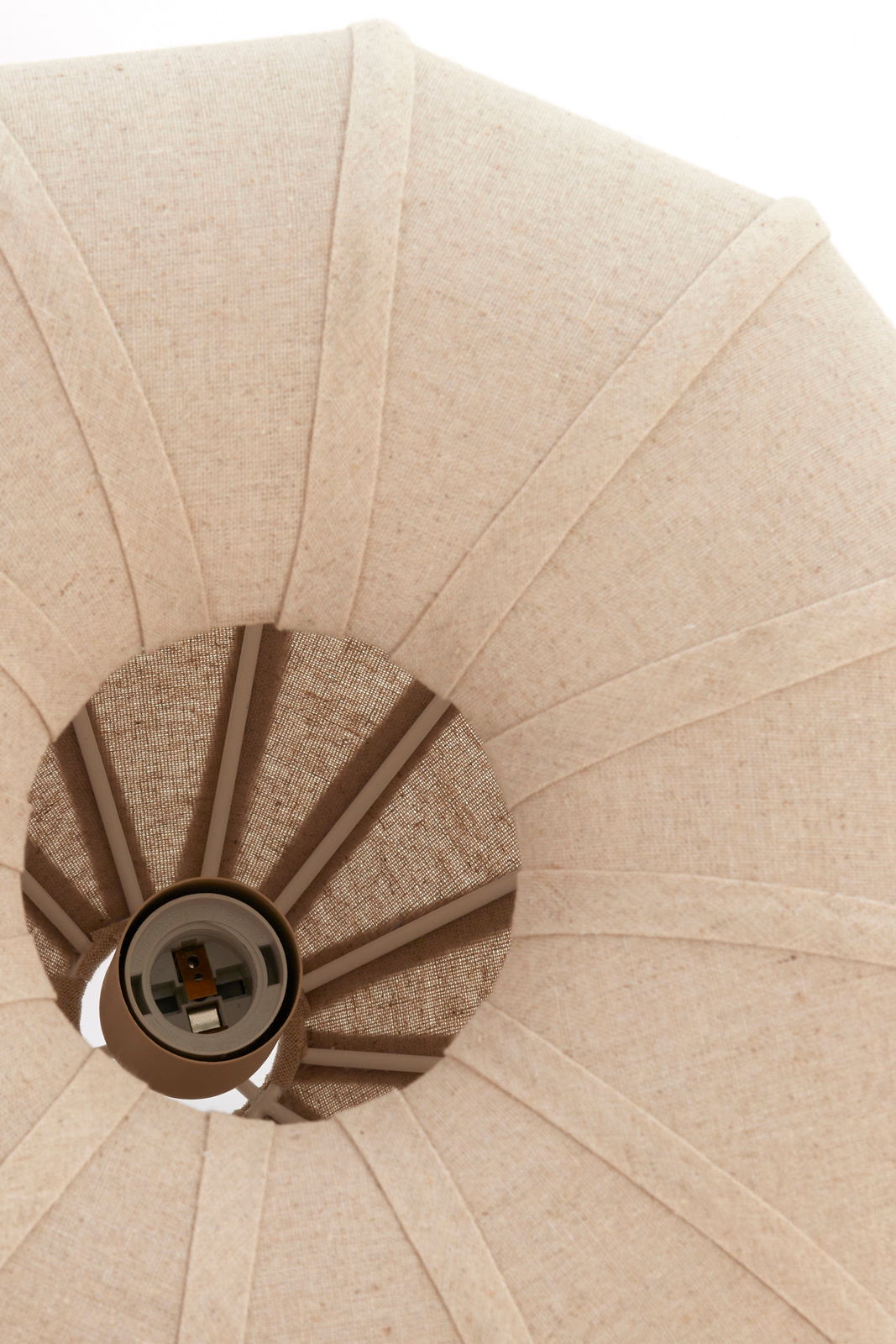 Nahaufnahme einer Hängeleuchte von unten, die einen textilen Lampenschirm in Beige zeigt.