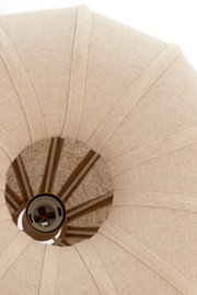 Nahaufnahme einer Hängeleuchte von unten, die einen textilen Lampenschirm in Beige zeigt.
