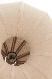 Nahaufnahme einer Hängeleuchte von unten, die einen textilen Lampenschirm in Beige zeigt.